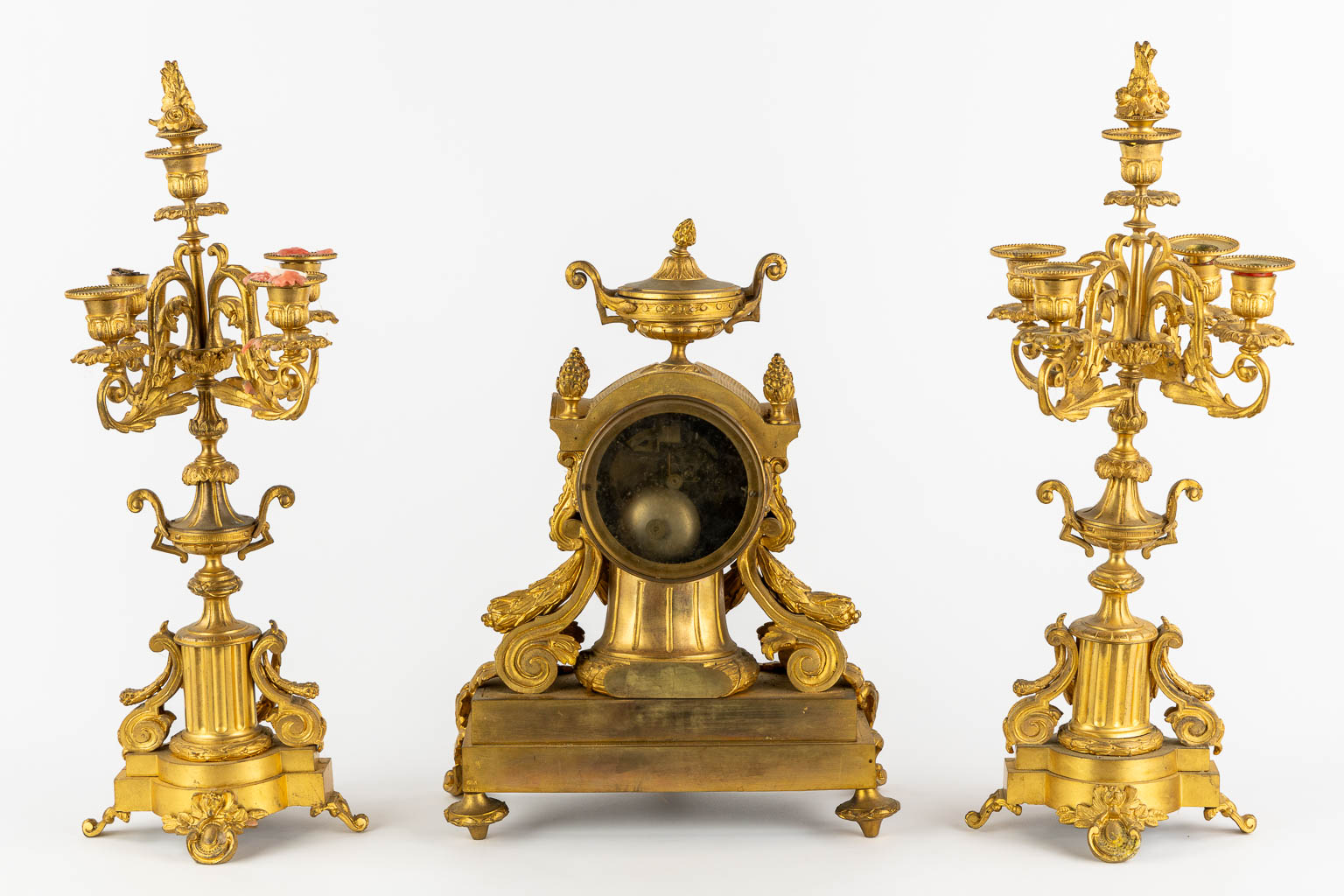Een driedelige schouwgarnituur, klok met kandelaars, verguld brons. 19de eeuw. (L:20 x W:32 x H:43 cm)