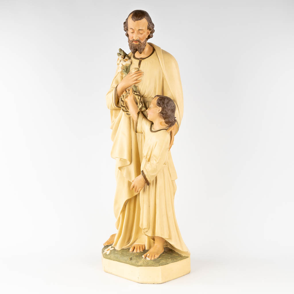 A large figurine of Joseph with Child, made of patinated plaster. Circa 1900. (H: 86 cm)