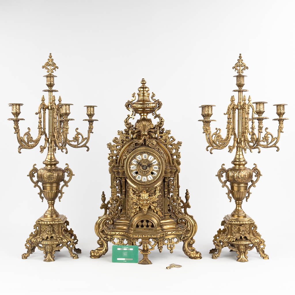 A three-piece mantle garniture consisting of a clock with candelabra, made of bronze. circa 1970. (W:36 x H:60 cm)