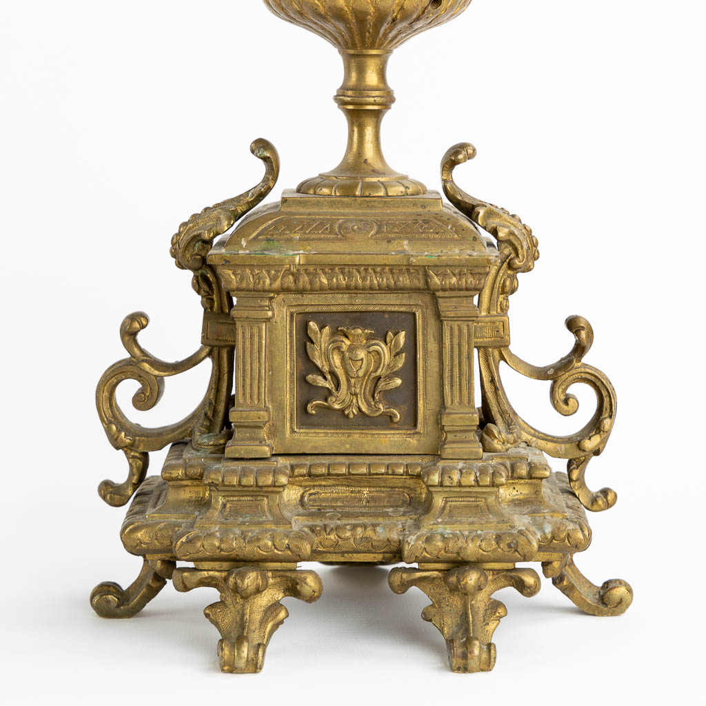 A three-piece mantle garniture clock and candelabra, patinated bronze. (L:16 x W:33 x H:50 cm)