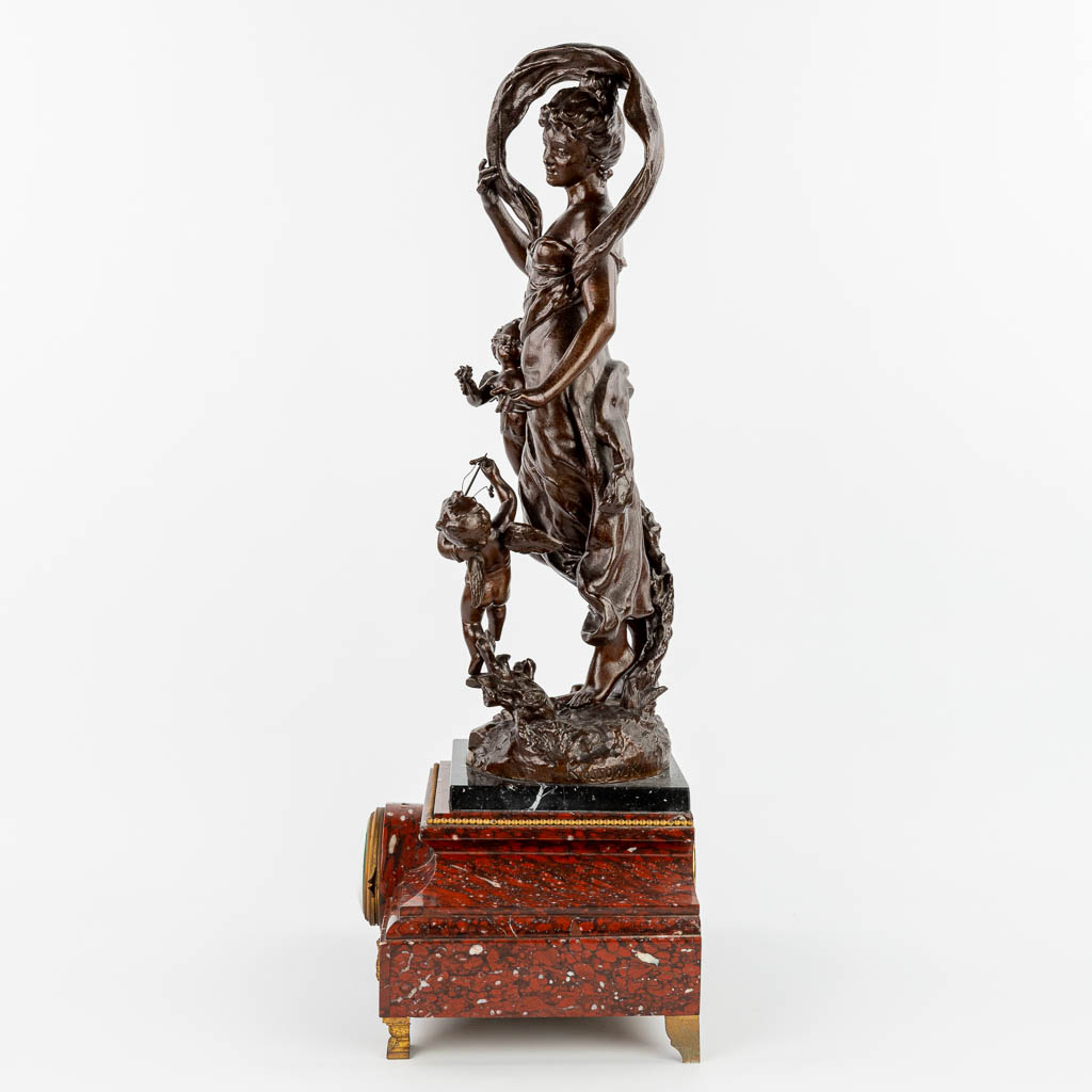 Henry KOSSOWSKI (1855-1921) A mantle clock made of red marble with a statue made of spelter and decorated with putti. (H:79cm)