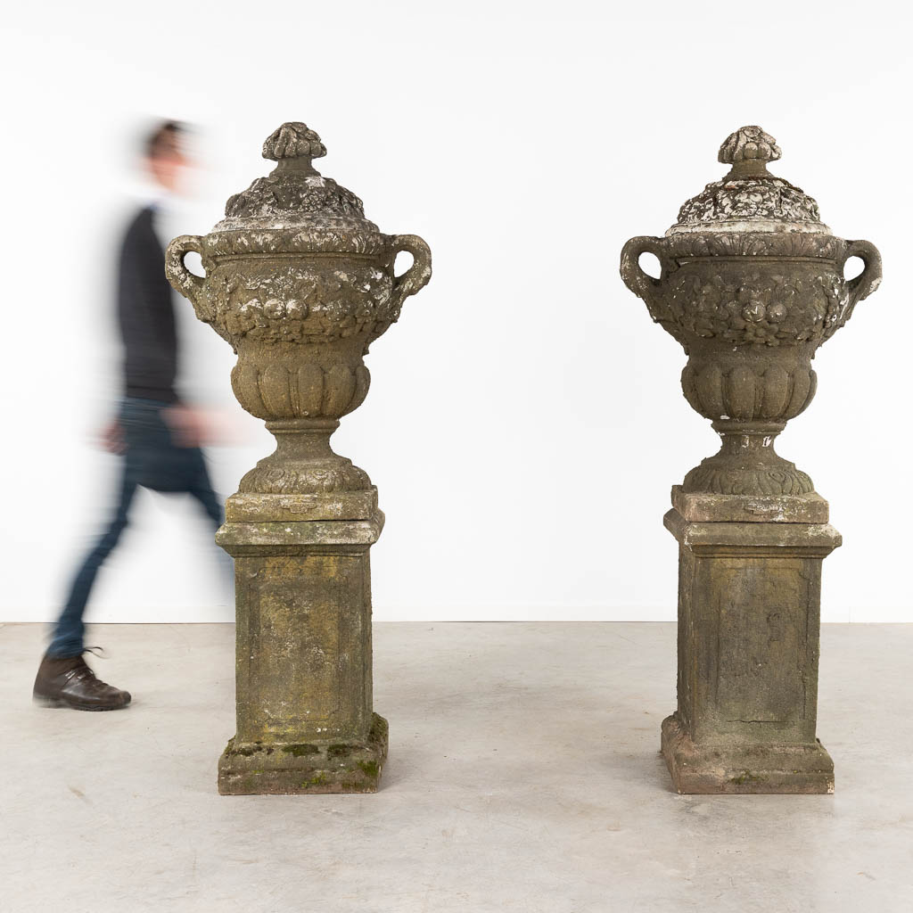 Een paar grote urnes met een deksel, staande op een pedestal, beton, 20ste eeuw. (D:50 x W:67 x H:173 cm)