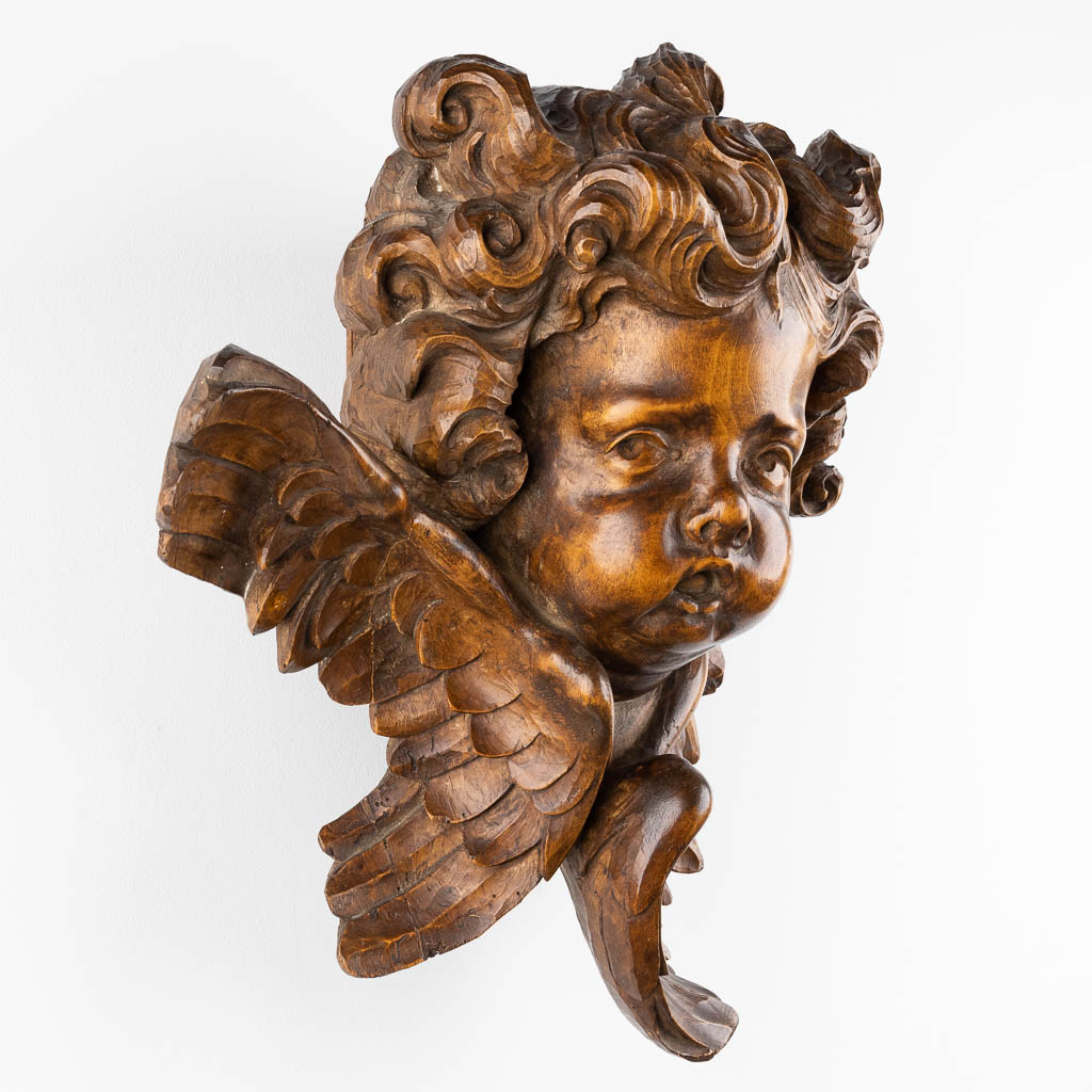 A wood-sculptured large head of an angel, Baroque style, 19th C. (D:27 x W:42 x H:48 cm)