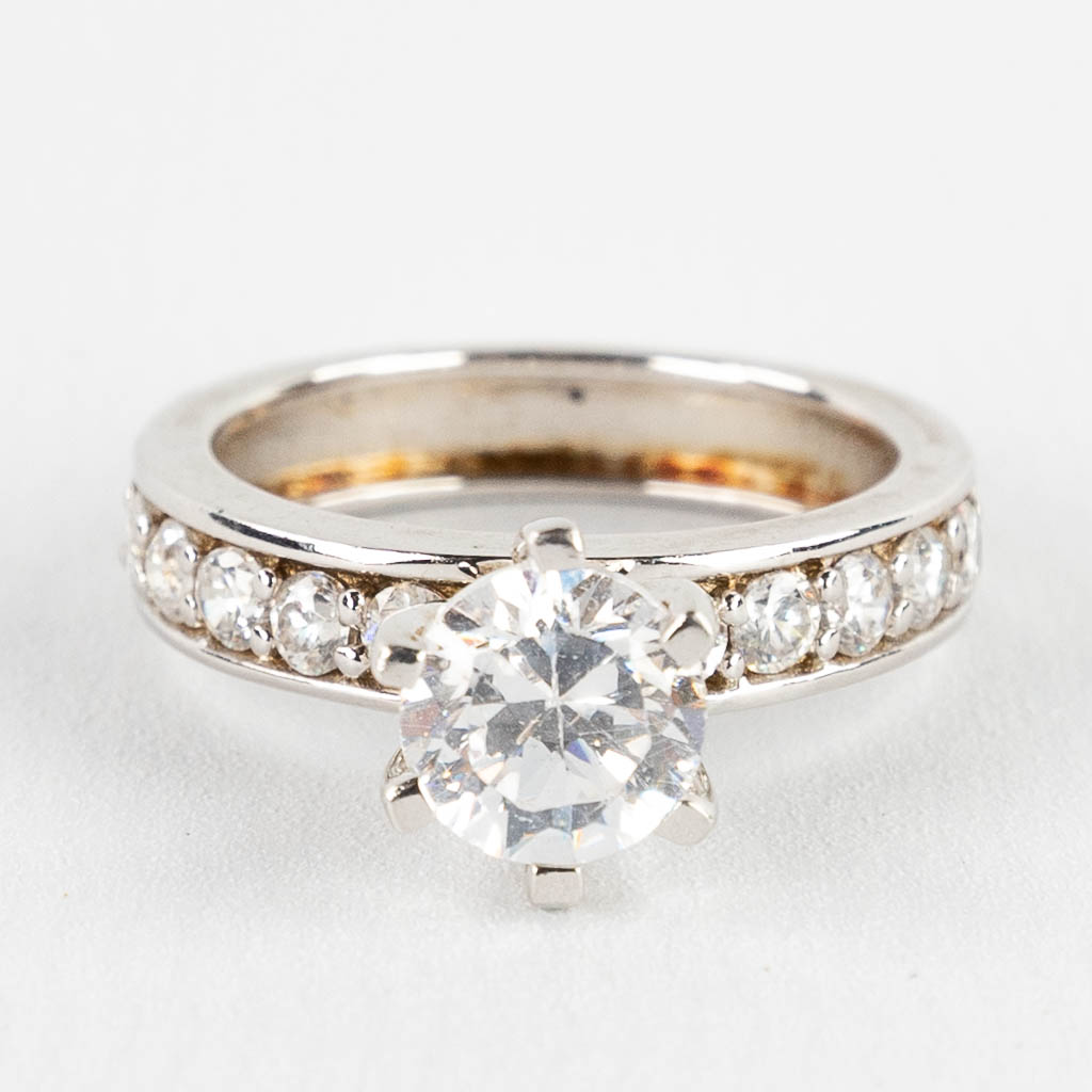 Een ring met grote solitaire en kleinere 'synthetische' stenen. Zilver, gemerkt 925.