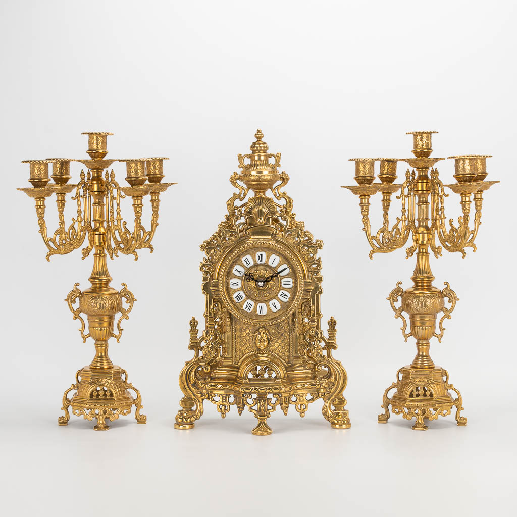 A 3 piece garniture clockset made of bronze, consisting of a clock and 2 candelabra. Battery operated movement. 