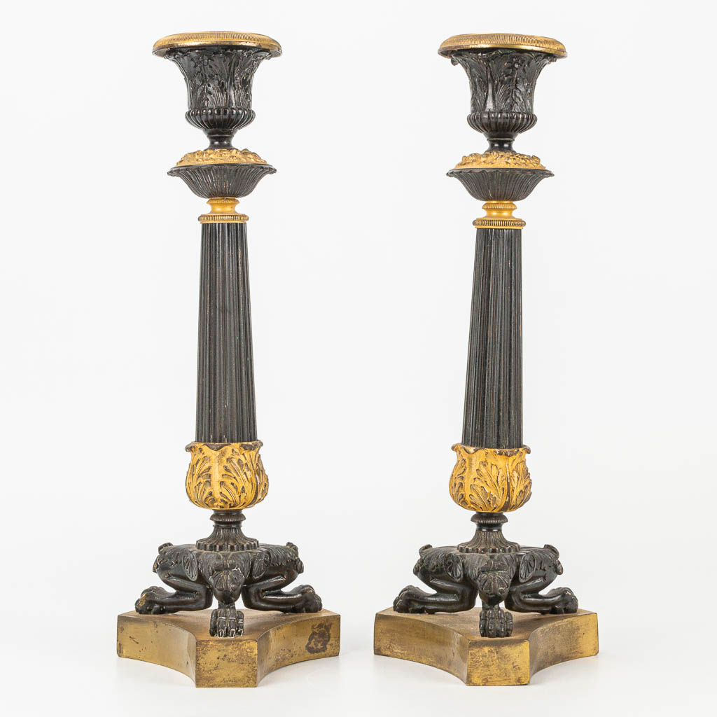 A pair of candlesticks made of gilt and patinated bronze in empire style. 