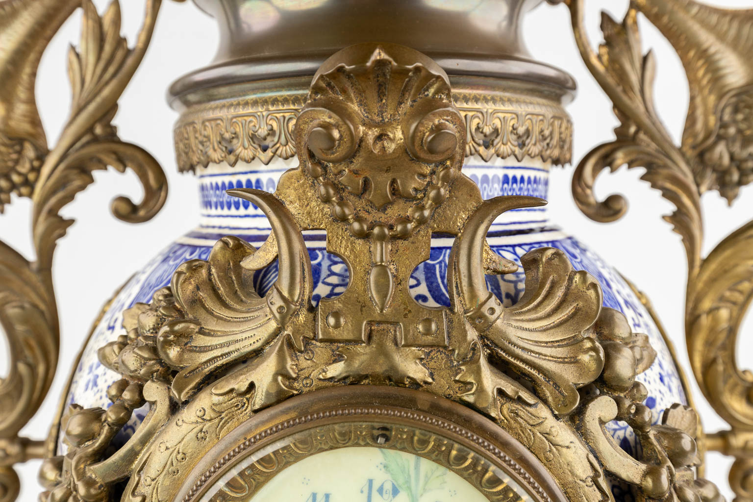 Een schouwklok, Delfts porselein gemonteerd met brons en afgewerkt met een arend. Circa 1900. (D:25 x W:44 x H:81 cm)