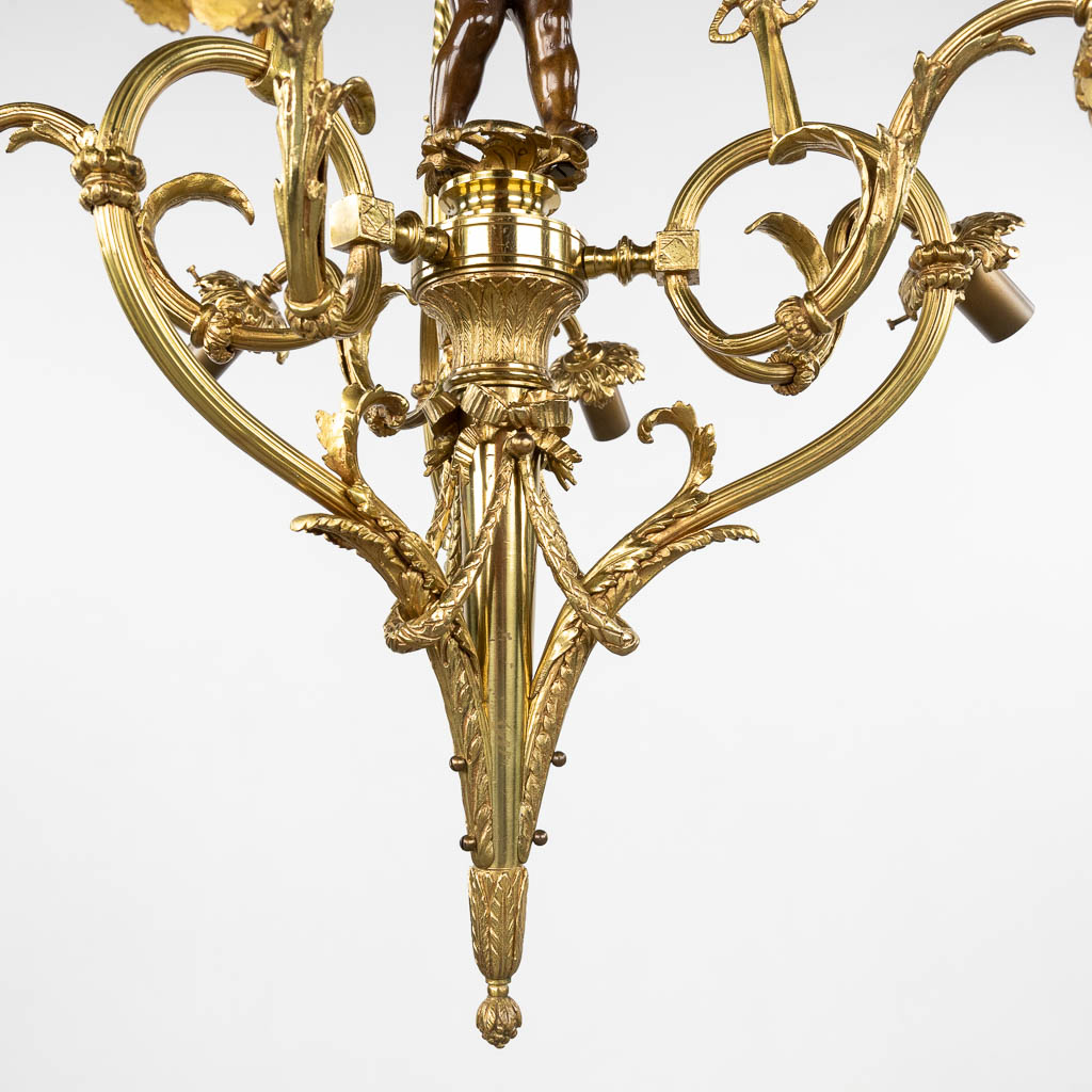 Een luchter, verguld en gepatineerd brons, decor met een putto en glazen rozen lampenkappen. 20ste eeuw. (H:100 x D:66 cm)