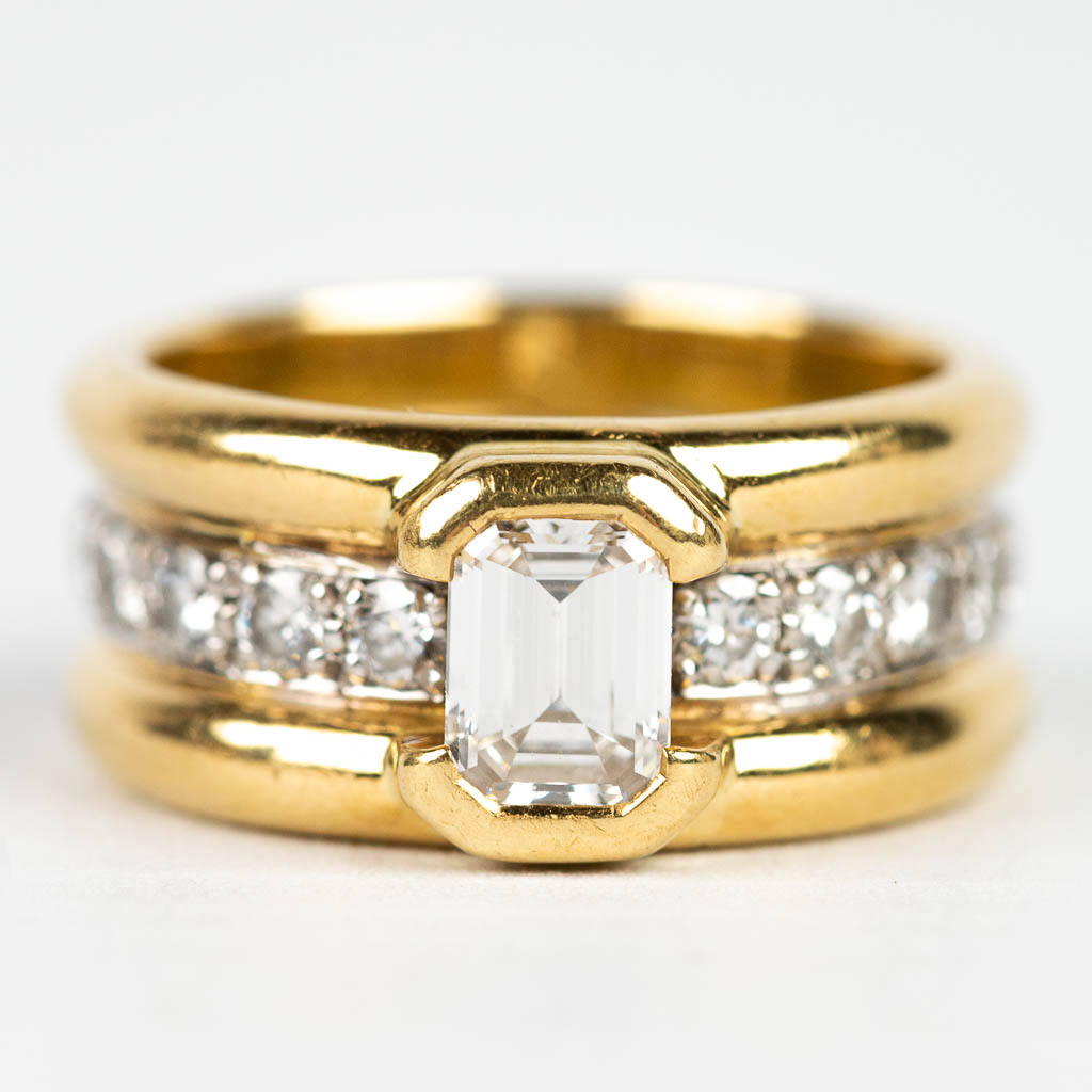 Een uitzonderlijke ring met 10 briljanten en 1 emerald cut diamant van ongeveer 1 kt. 