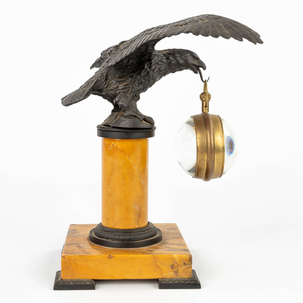 A pocket watch holder in the shape of an eagle mounted on a marble stand. (H:20,5cm)