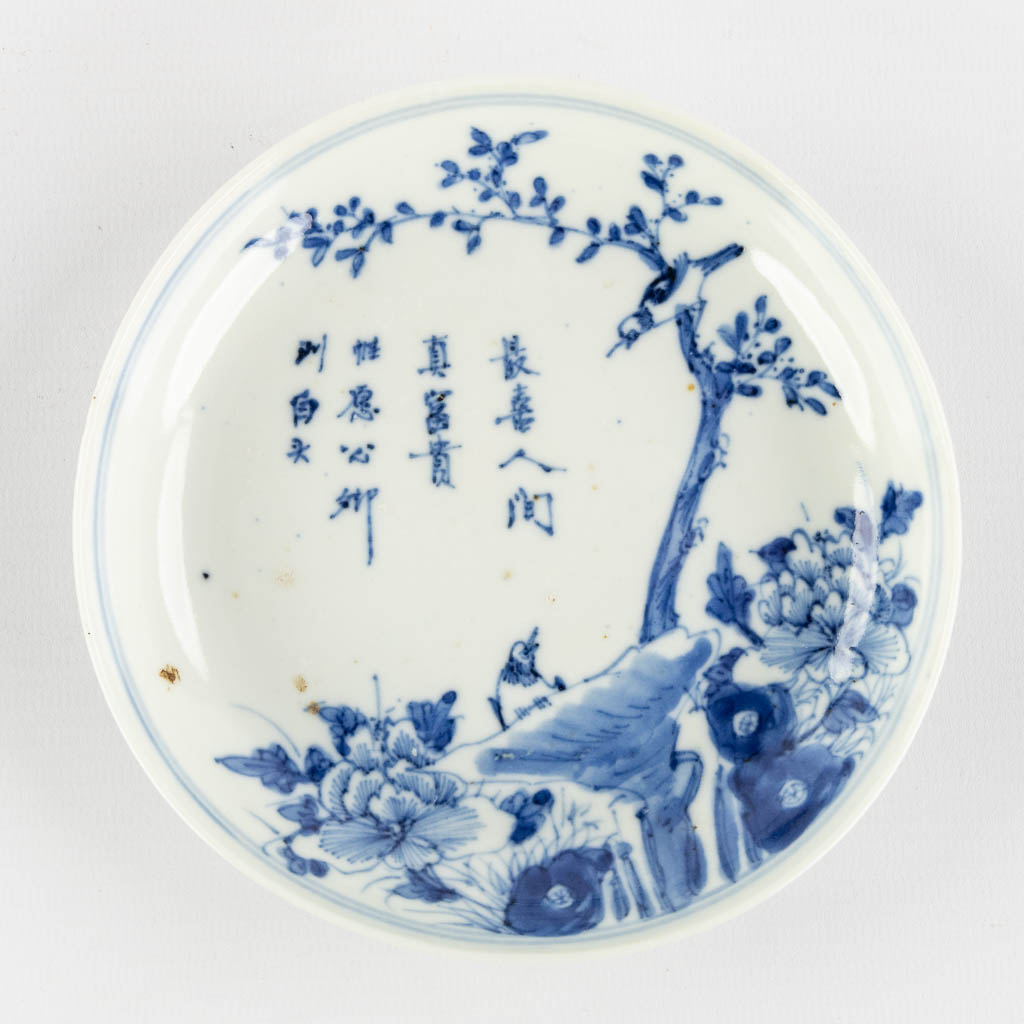 Een Chinees sierbord, blauw-wit met decor van Fauna en Flora, Kangxi merk. (H:3 x D:13,5 cm)