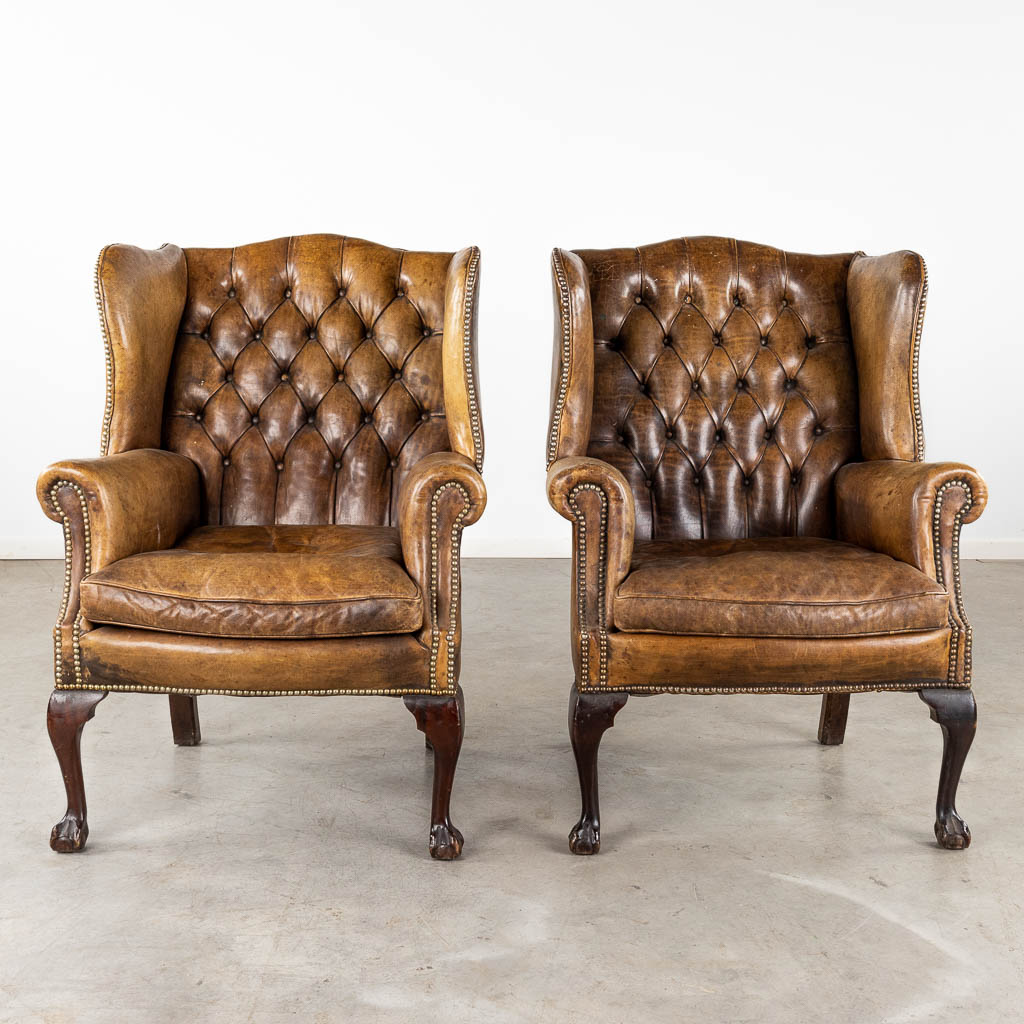 A pair of armchairs, Chesterfield style, leather and wood. (D:85 x W:78 x H:107 cm)