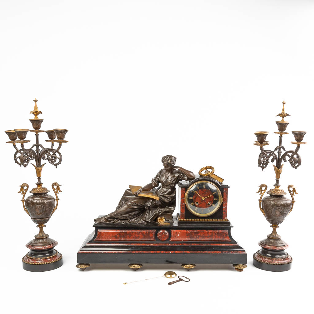 A three-piece garniture clock with candelabra, made of marble. Mounted with patinated and gilt bronze