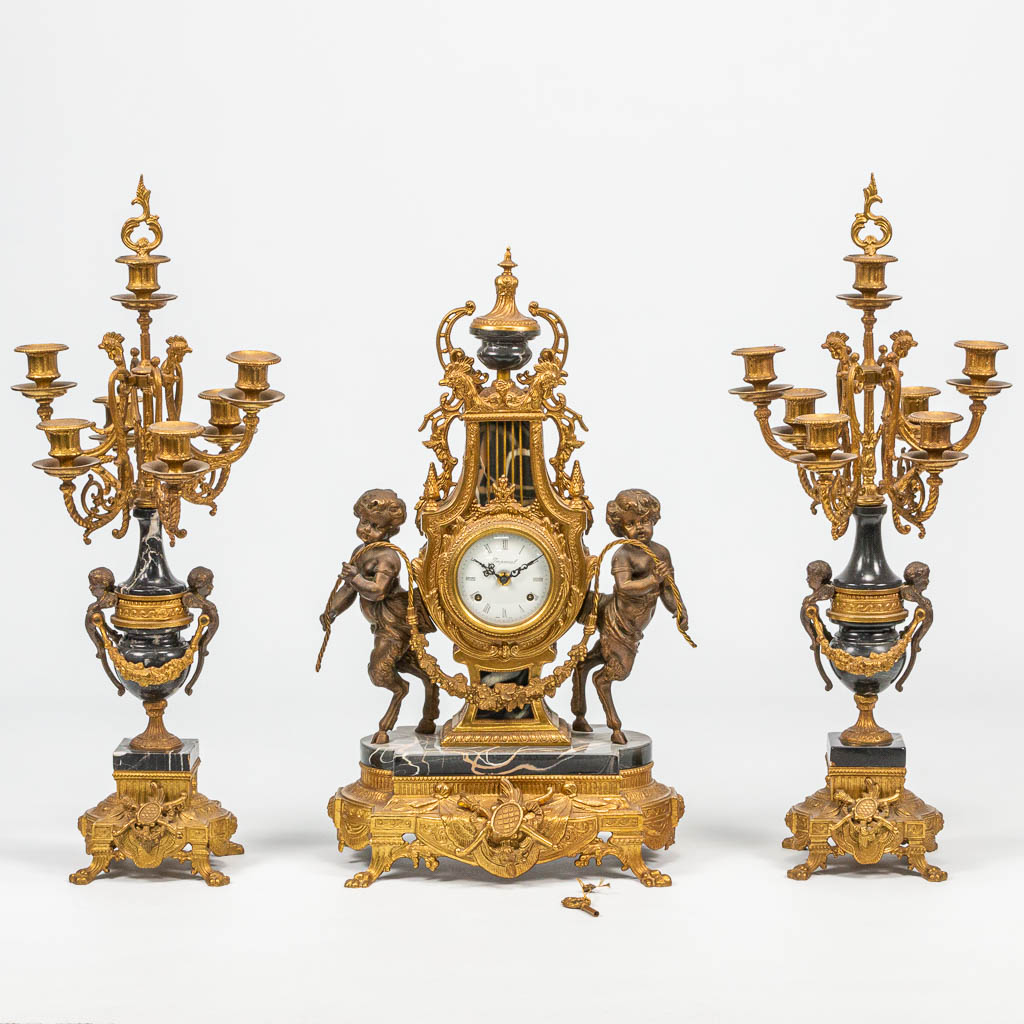 A 3 piece garniture clock in empire style and finished with black marble. The second half of the 20th century. 