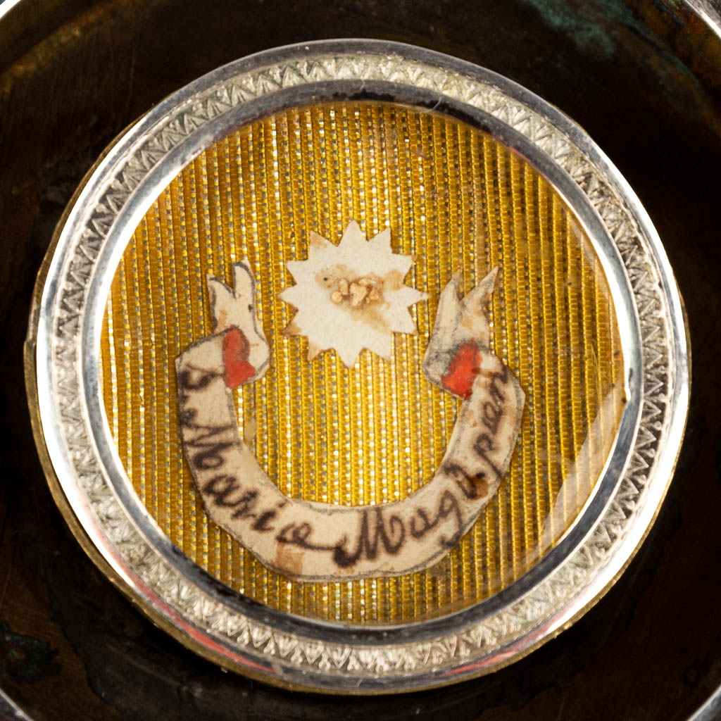 Een verzegelde theca met relikwie S. Maria Magdalena, in een zilveren en messing relikwiehouder. (W:12 x H:13 cm)