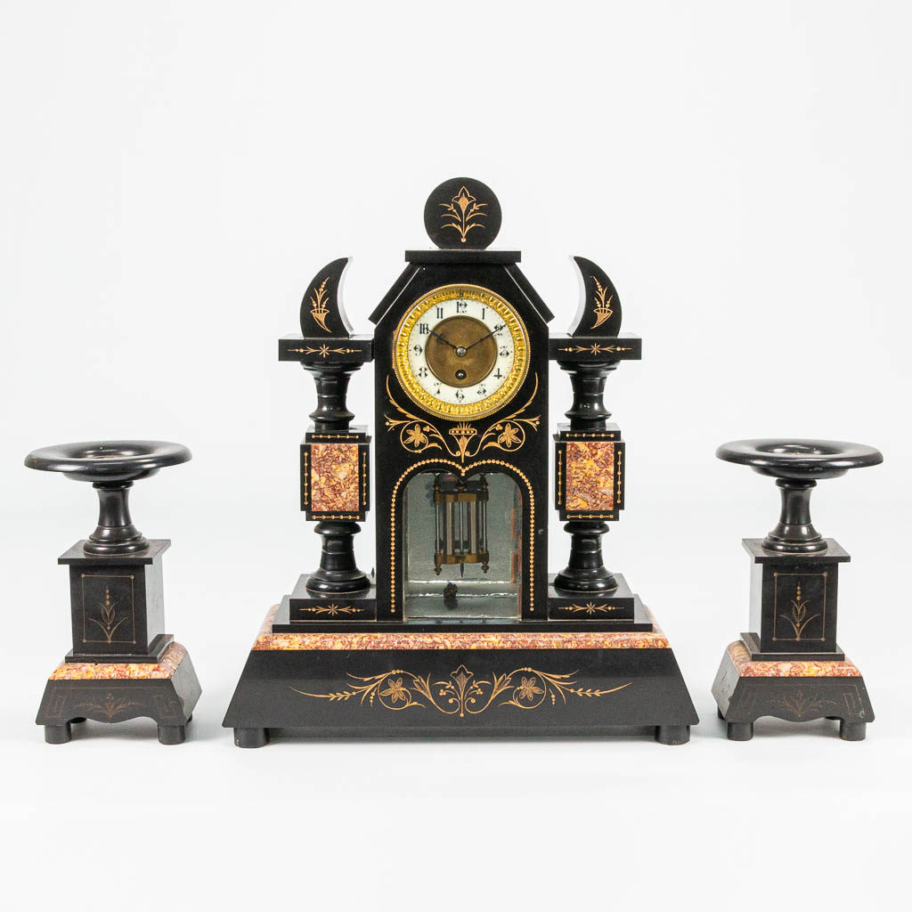 A 3 piece garniture clock made of black marble with engravings. 19th century. 