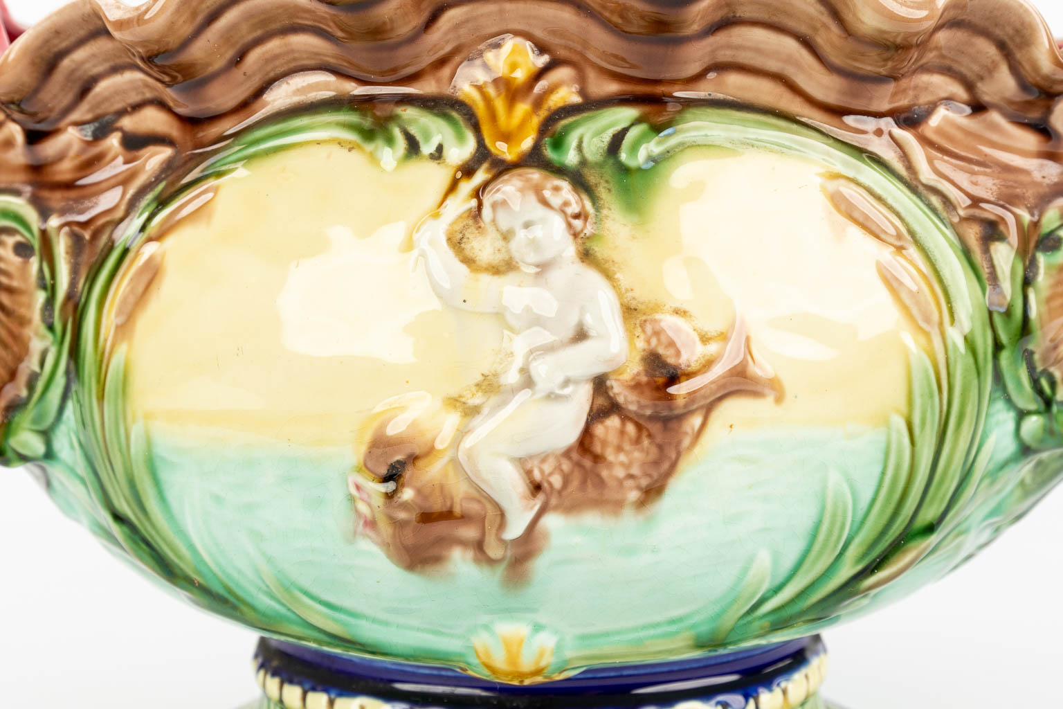 Een cache-pot gemaakt uit geglazuurde faience in art nouveau stijl versierd met vissen en putti. (H:26cm)