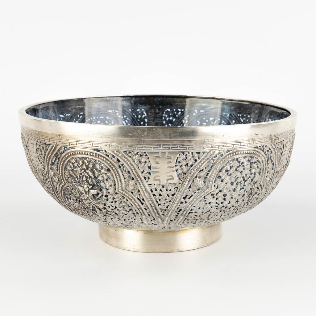 An Asian bowl, silver with a blue glass liner, decorated with bats and lotus flowers. 320g. (H:10 x D:22,5 cm)