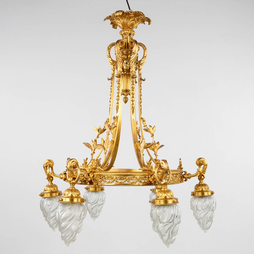 Een grote luchter, verguld brons met glazen 'Flambeaux' lampenkappen. Circa 1900. (H:90 x D:76 cm)