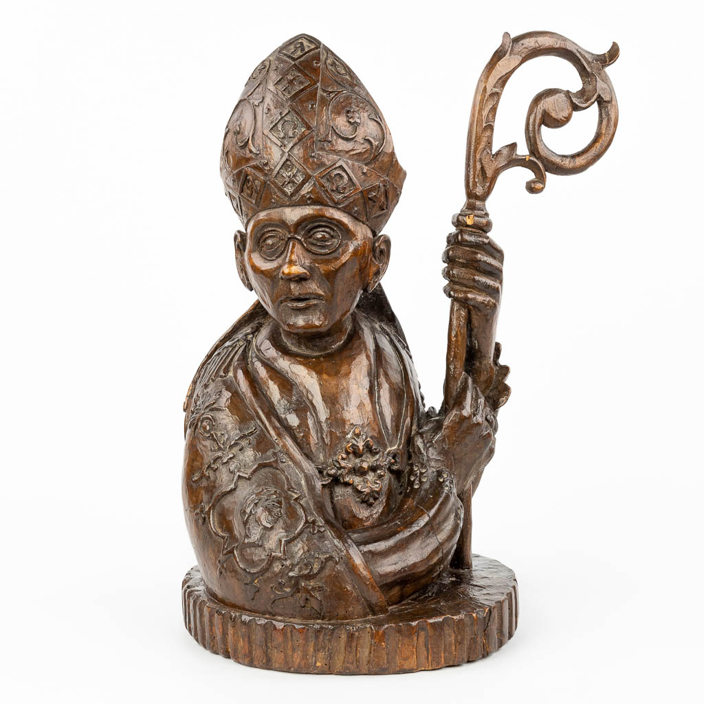 A richly decorated wood sculpture of a pope or Holy figurine with mitre and staff. 
