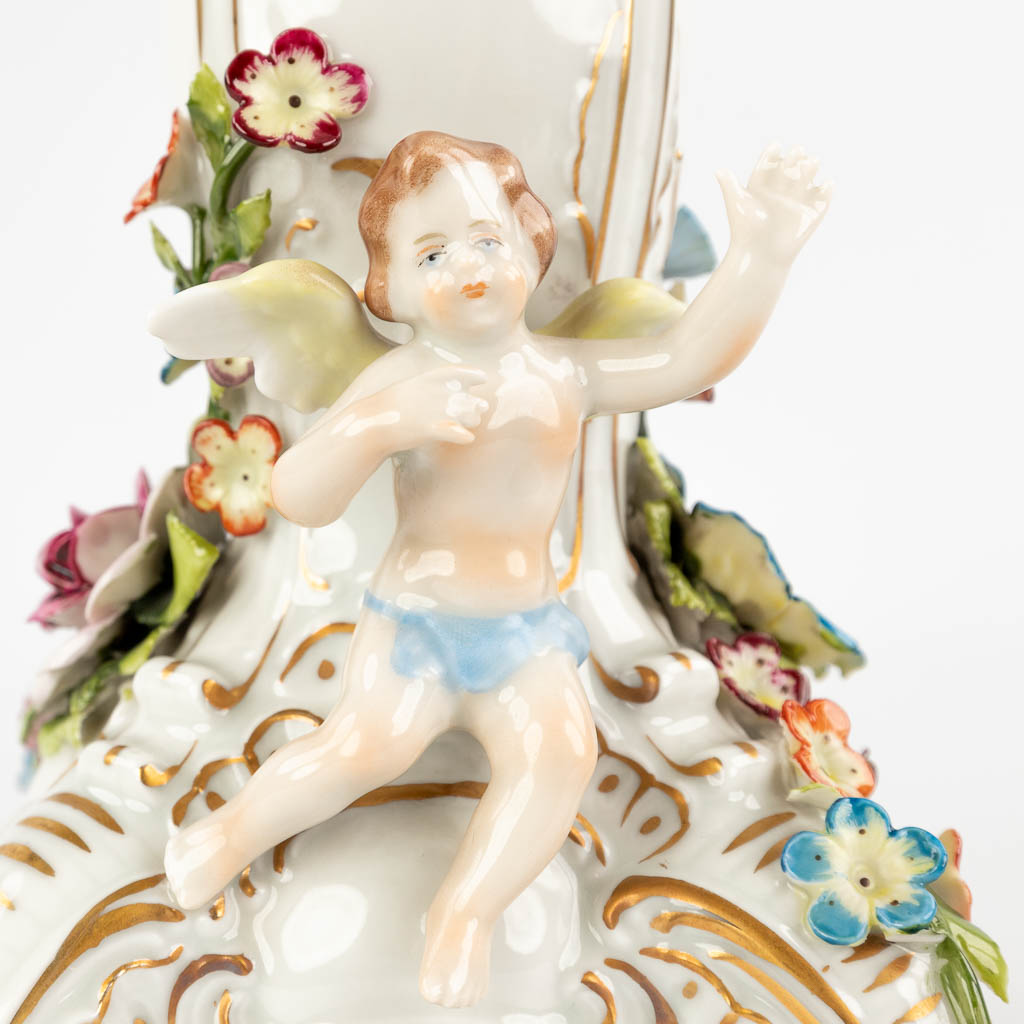 A table candle holder, porcelain decorated with flowers and putti. 20th C. (D:38 x W:38 x H:47 cm)