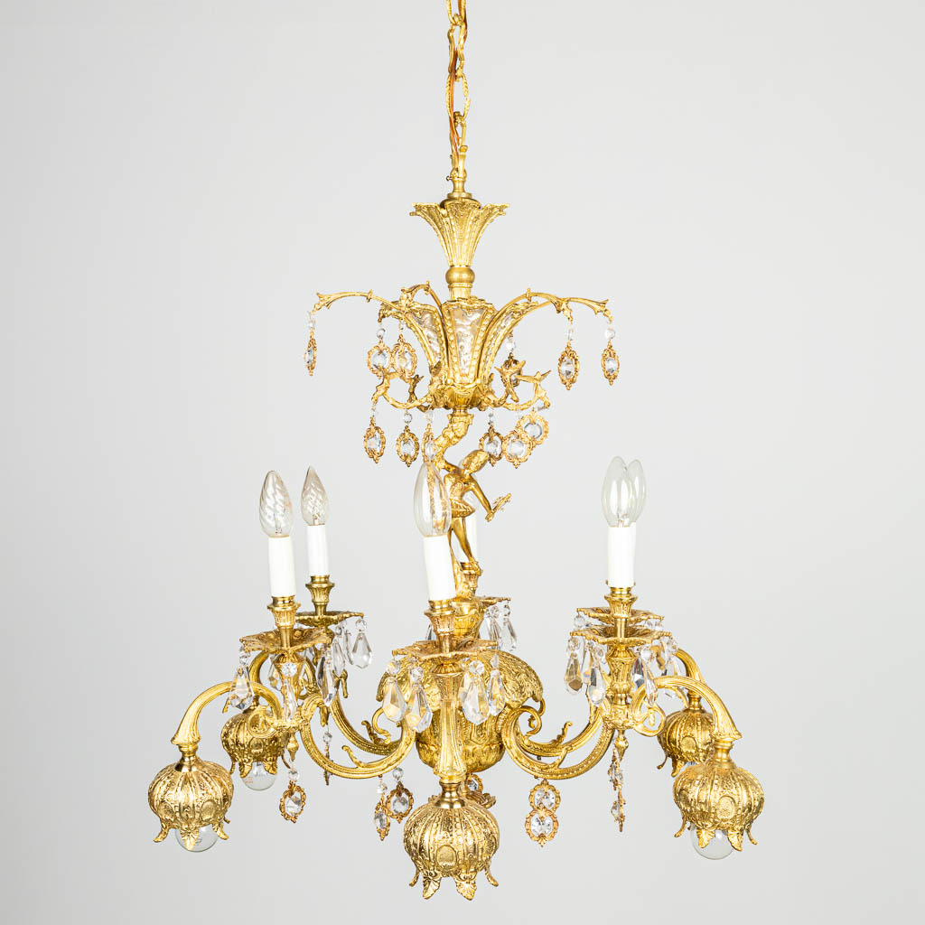 A chandelier made of brass and glass, decorated with birds and a ballet dancer
