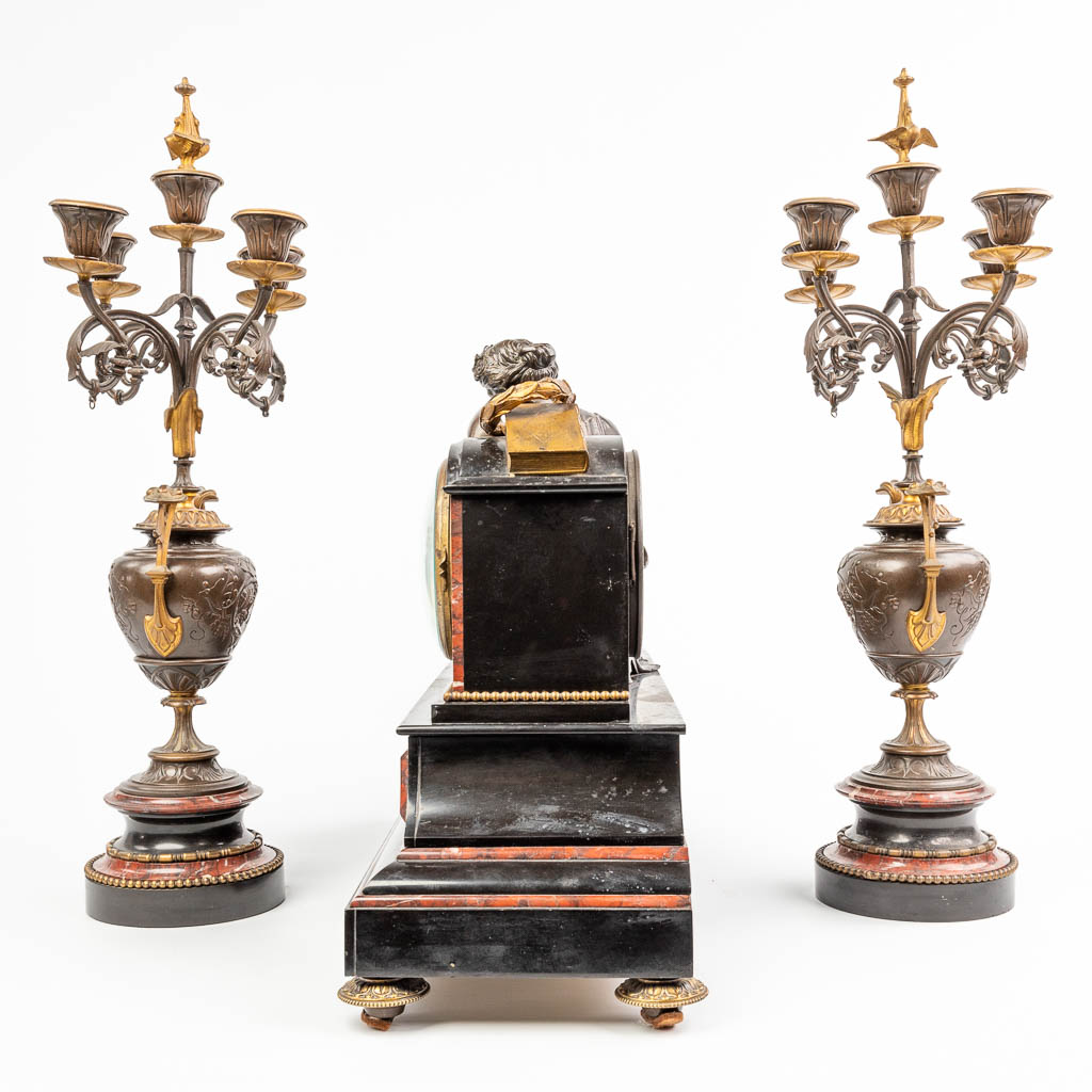 A three-piece garniture clock with candelabra, made of marble. Mounted with patinated and gilt bronze