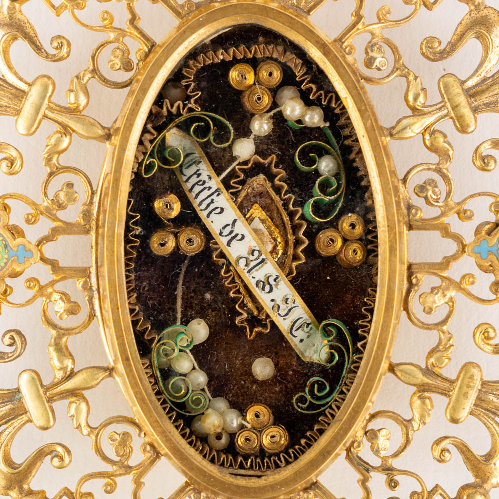 Een theca met relikwie voor de Kribbe van Jezus Christus, DNJC, in een messing relikwiehouder. (W:9,5 x H:13 cm)