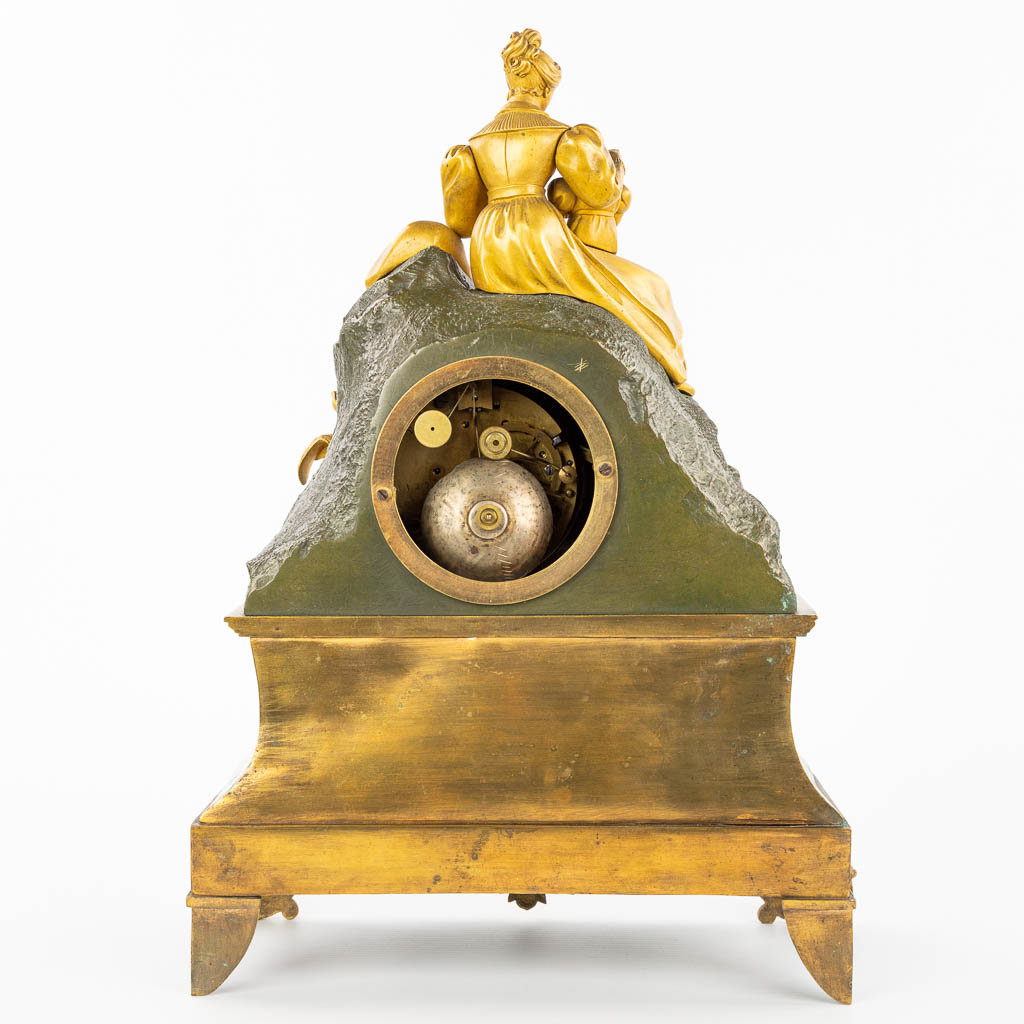 Een tafelklok gemaakt uit verguld en gepatineerd brons in empire stijl. Moeder met kind. (H:38cm)