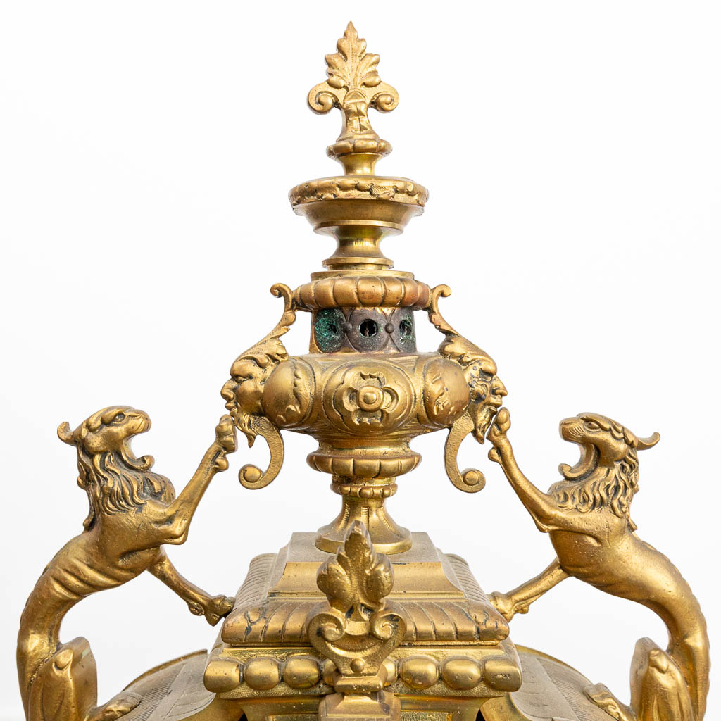 Een driedelige schouwgarnituur gemaakt uit brons bestaande uit een klok met twee kandelaars. (H:70cm)