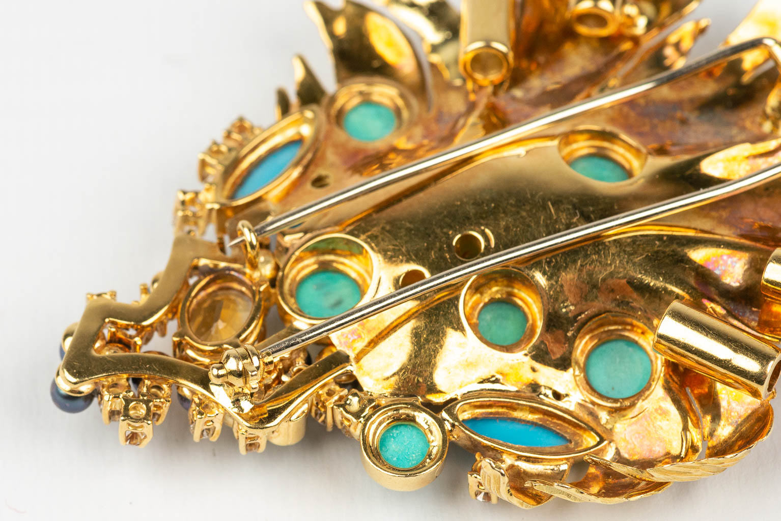 A large brooch decorated with multiple different precious stones, diamonds, in an 18 karat yellow gold design. 