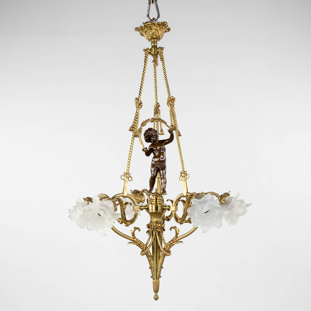 A ceiling lamp, gilt and patinated bronze, decorated with a putto and rose glass shades. 20th C. (H:100 x D:66 cm)