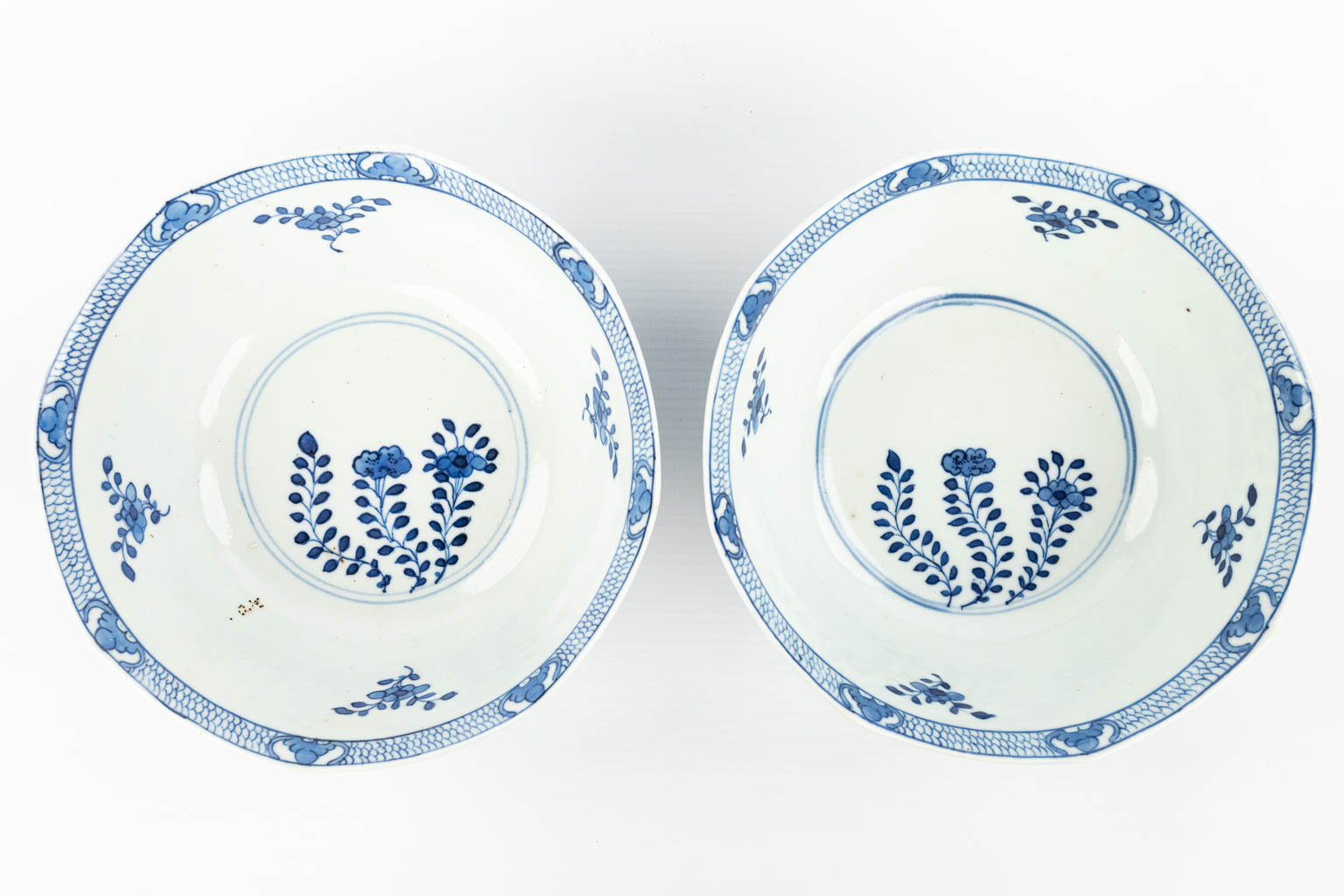 A pair of Chinese bowls made of porcelain with blue-white flower decor and marked Kangxi. (H:7,2cm)
