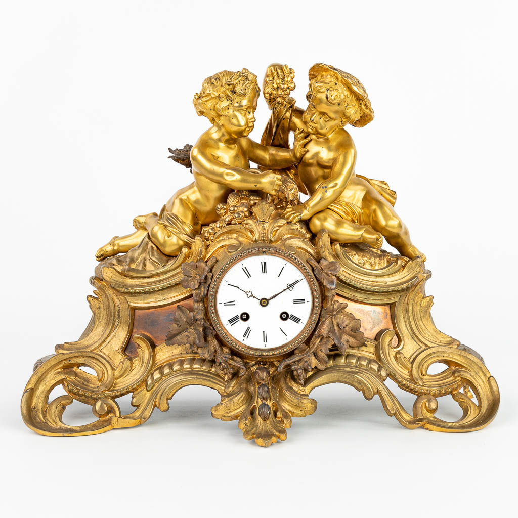Een schouw klok gemaakt uit verguld brons en versierd met putti in Lodewijk XV stijl. (H:36cm)