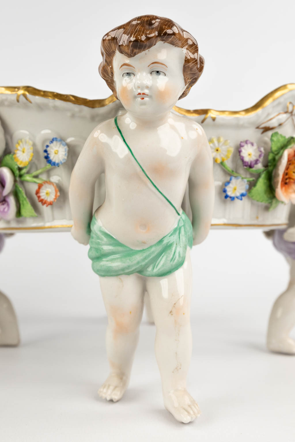 Two baskets, carried by putti. Polychrome German porcelain, 20th C. (H:17 x D:33 cm)