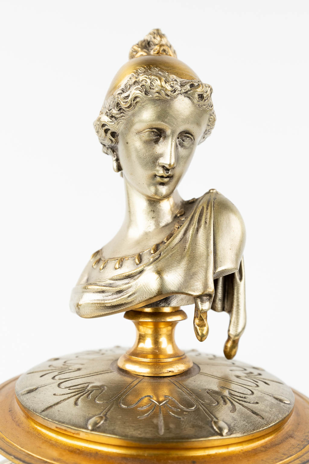 Een schouwklok gemaakt uit brons in Lodewijk XVI stijl. Circa 1900. (L: 23 x W: 29 x H: 42 cm)