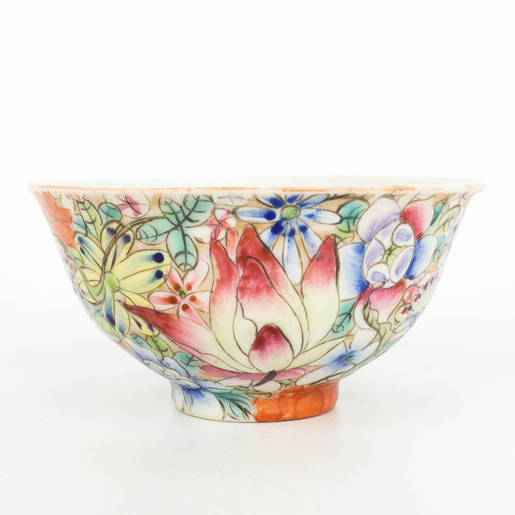 A Chinese porcelain bowl with a floral decor in a sculptured wood lotus flower stand. Marked Qianlong. (H:9,5cm)