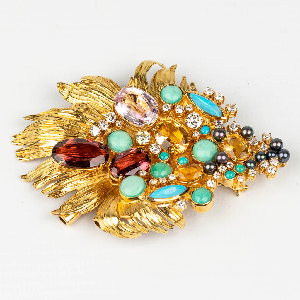 A large brooch decorated with multiple different precious stones, diamonds, in an 18 karat yellow gold design. 