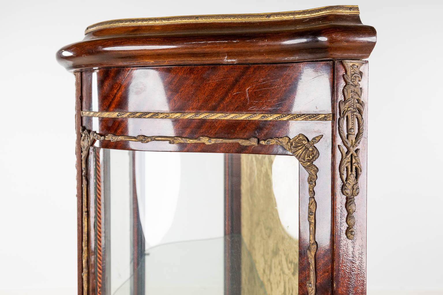 Een vintage vitrinekast afgewerkt met gebogen glas en brons in Lodewijk XV stijl. (L:35 x W:80 x H:140 cm)