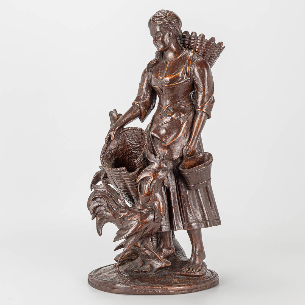 A wood sculpture of a lady with rooster, Black Forest. 