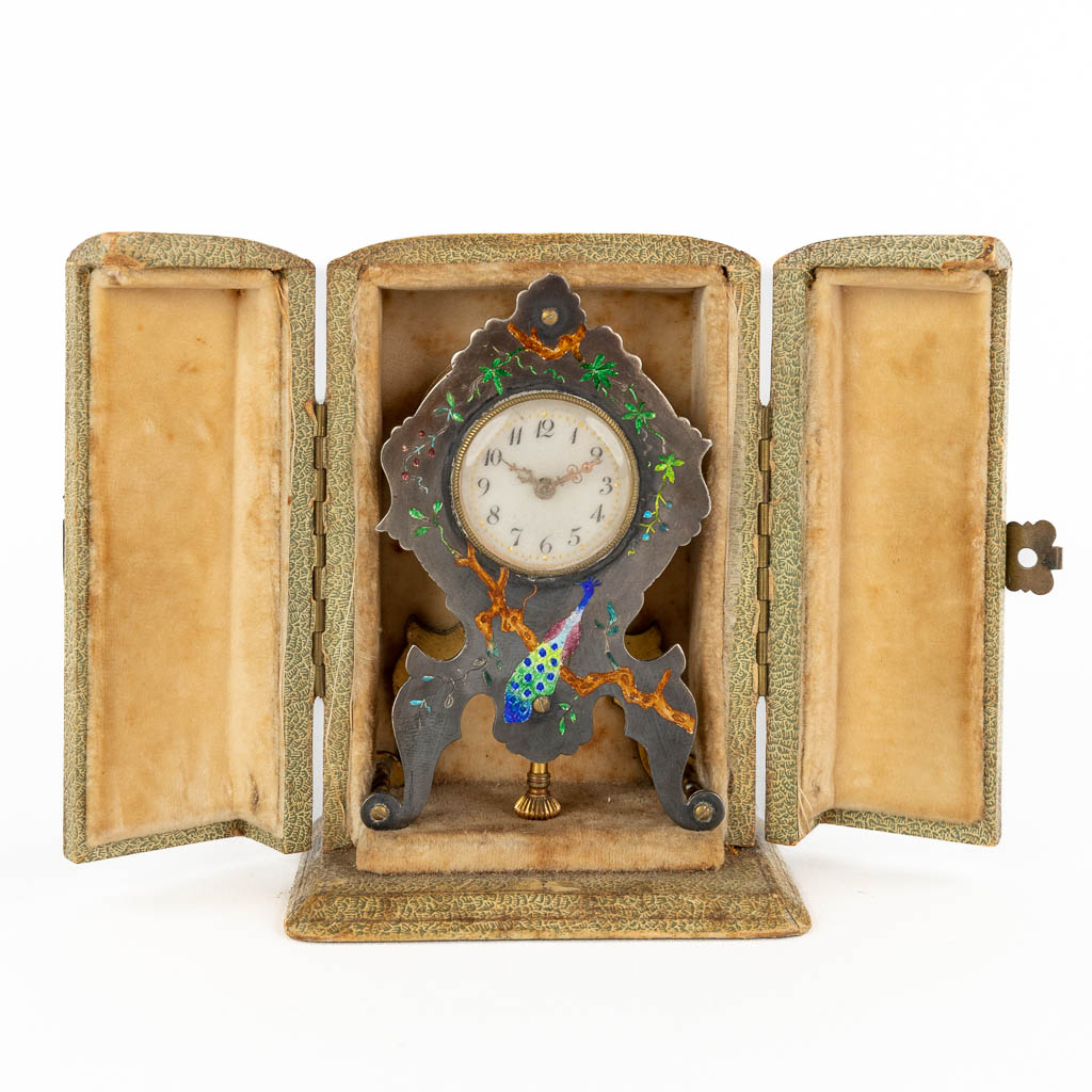 A traveller's clock, silver with hand-painted enamel. Decor of a peacock. Circa 1900. (D:2 x W:5,5 x H:9 cm)