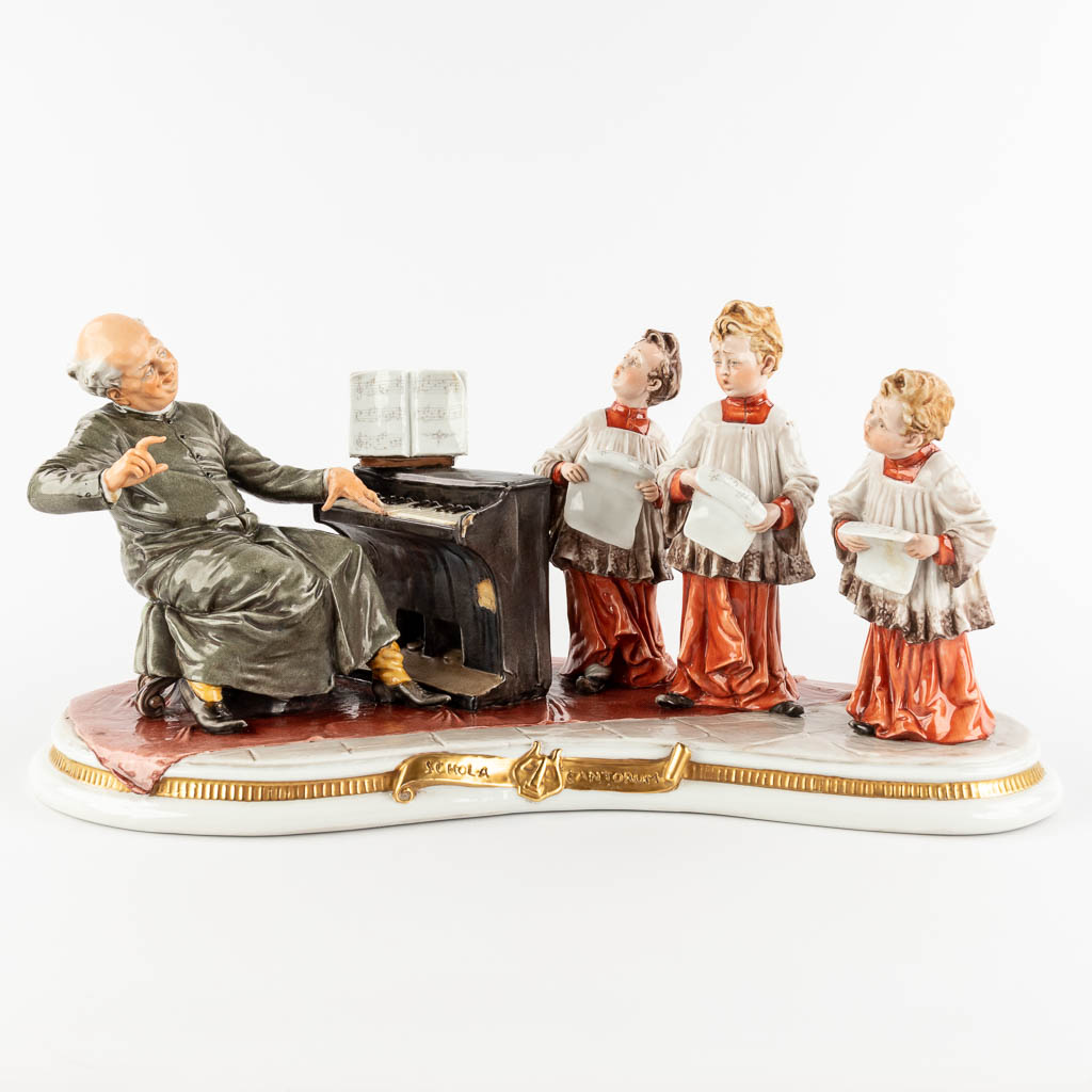 Capodimonte, 'Schola Cantoro', a porcelain group with a mechanical music box. 20th C. (D:23 x W:48 x H:22 cm)