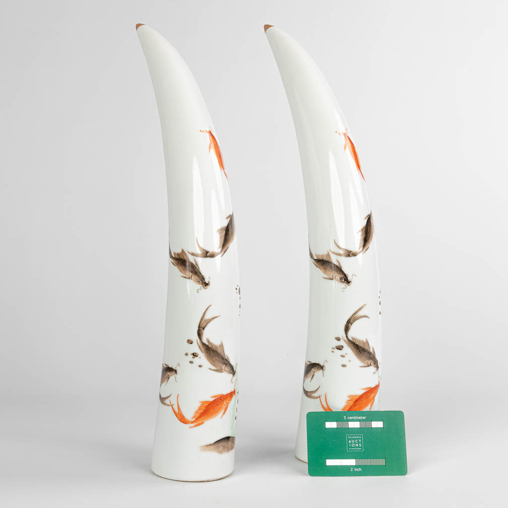 A pair of tusks, made of Chinese porcelain and decorated with fish.