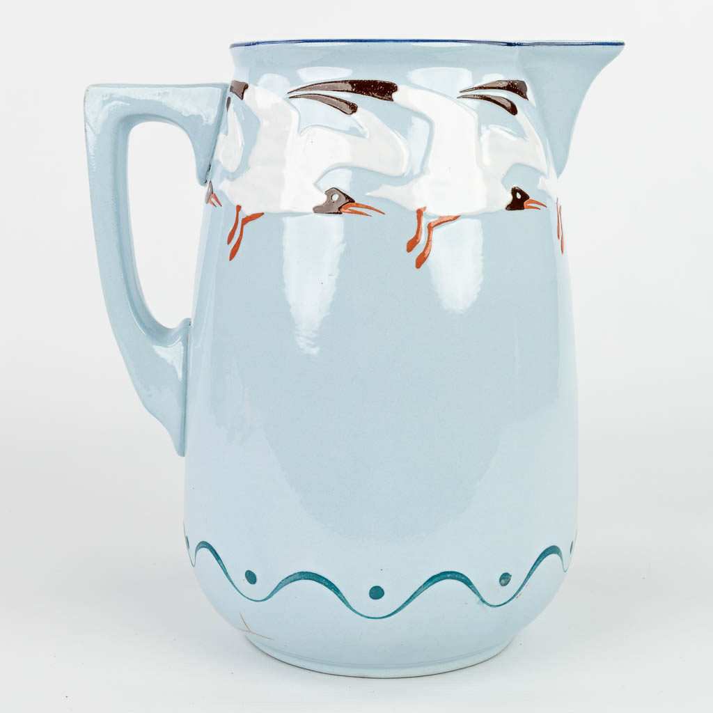 A jug and bowl made in art nouveau style with blue glaze and decorated with seagulls. Marked Sarreguemines. (H:14cm)