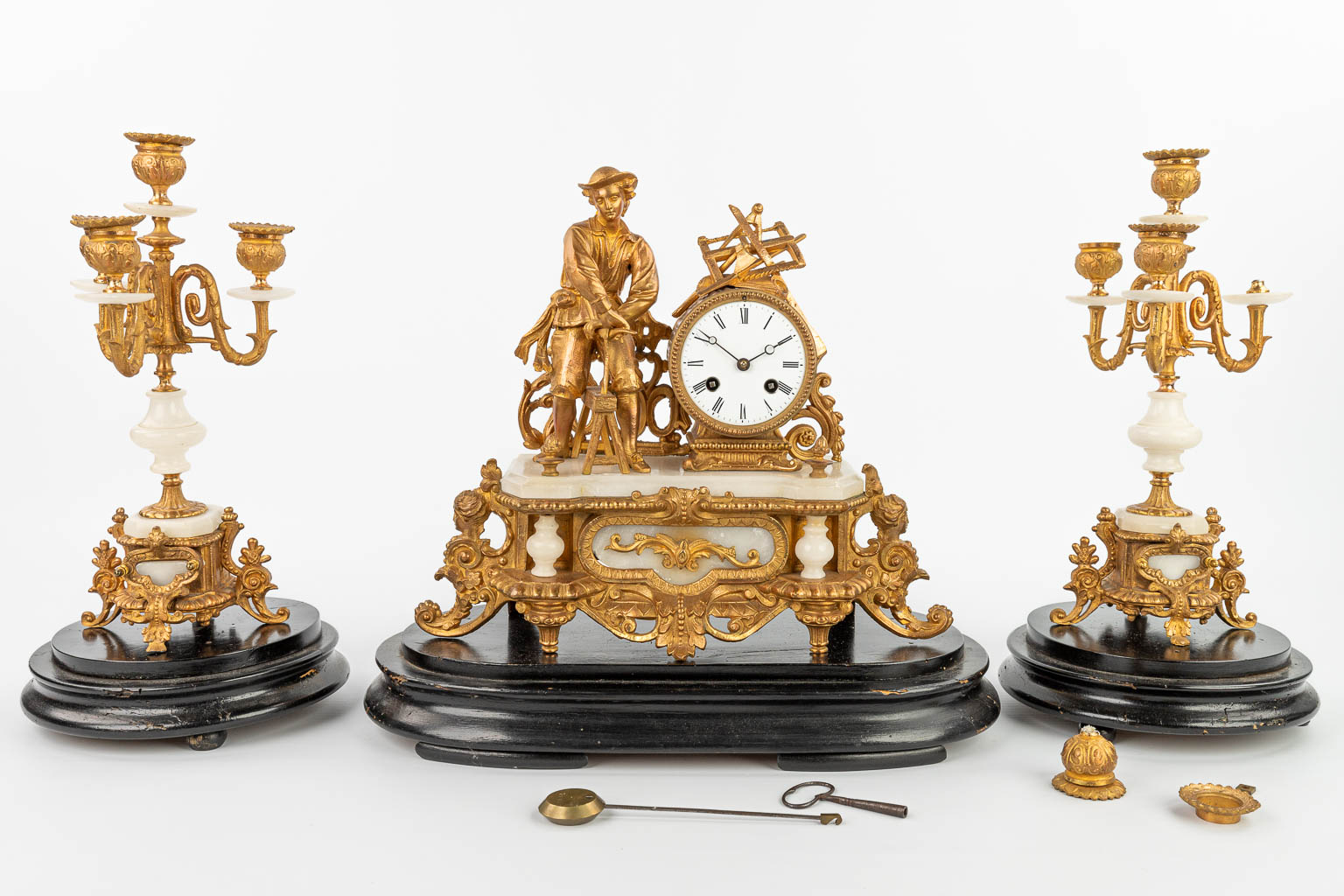 A three-piece mantle clock made of gilt spelter and alabaster, standing under three globes. (H:31cm)
