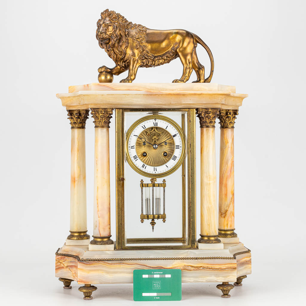 Een schouwklok gemaakt uit albast en versierd met een bronzen leeuw in neoklassieke stijl (H:52cm)