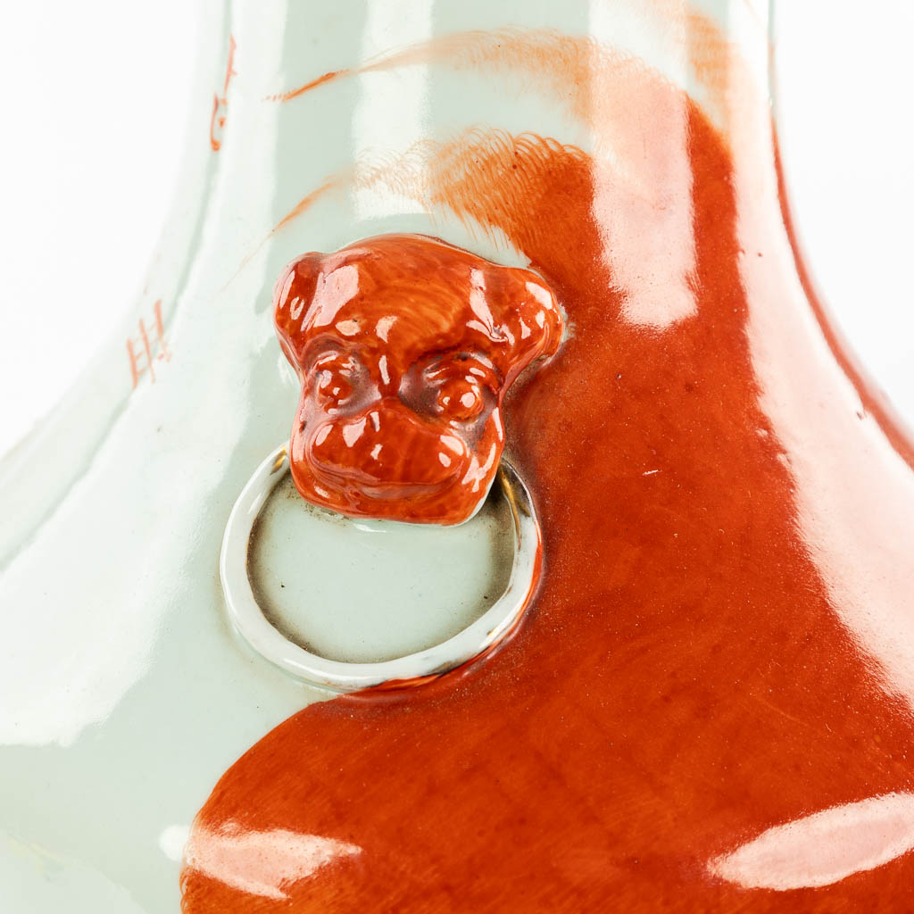 Een Chinese vaas gemaakt uit porselein en versierd met decor van een rode foo hond. (H:59cm)