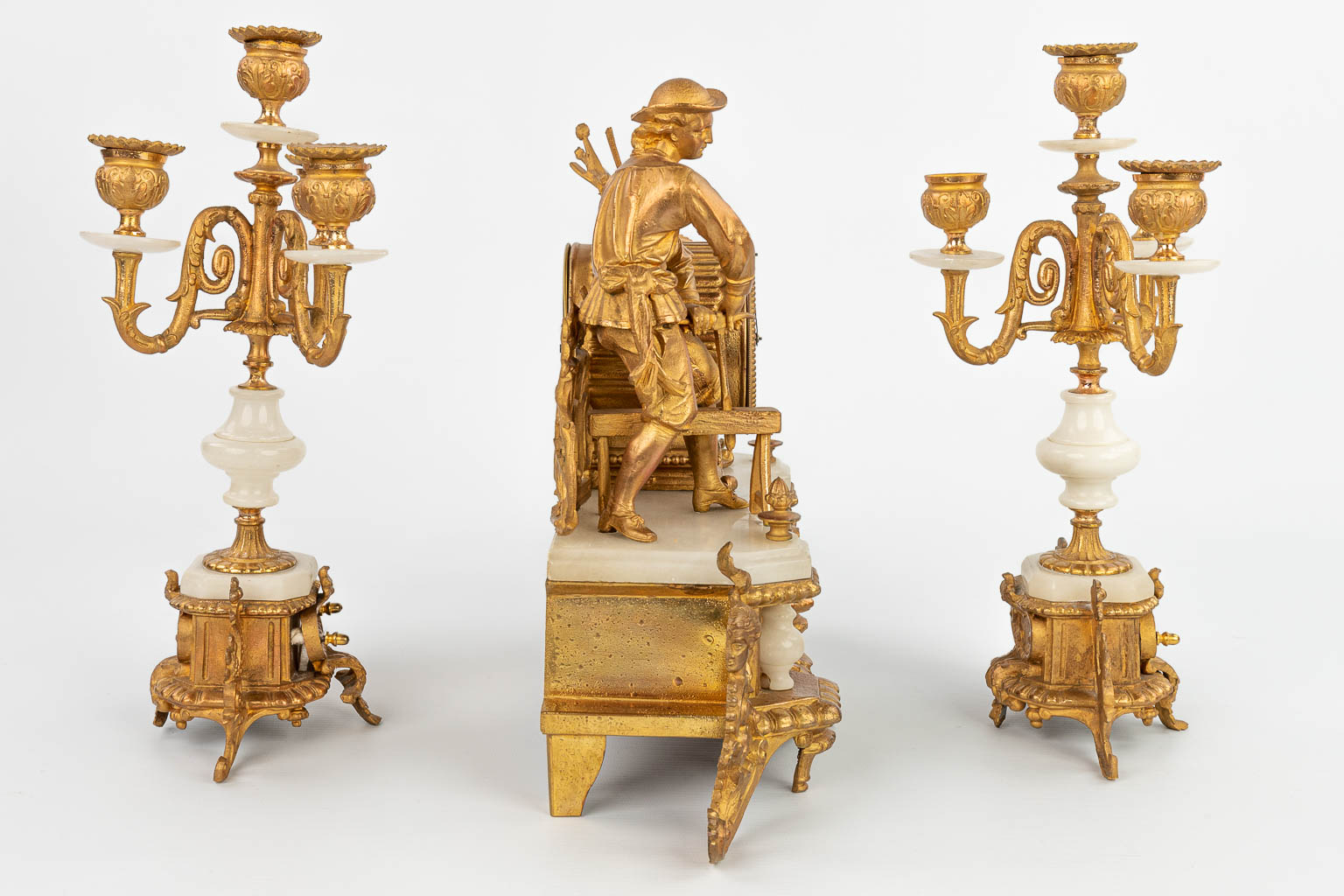 A three-piece mantle clock made of gilt spelter and alabaster, standing under three globes. (H:31cm)