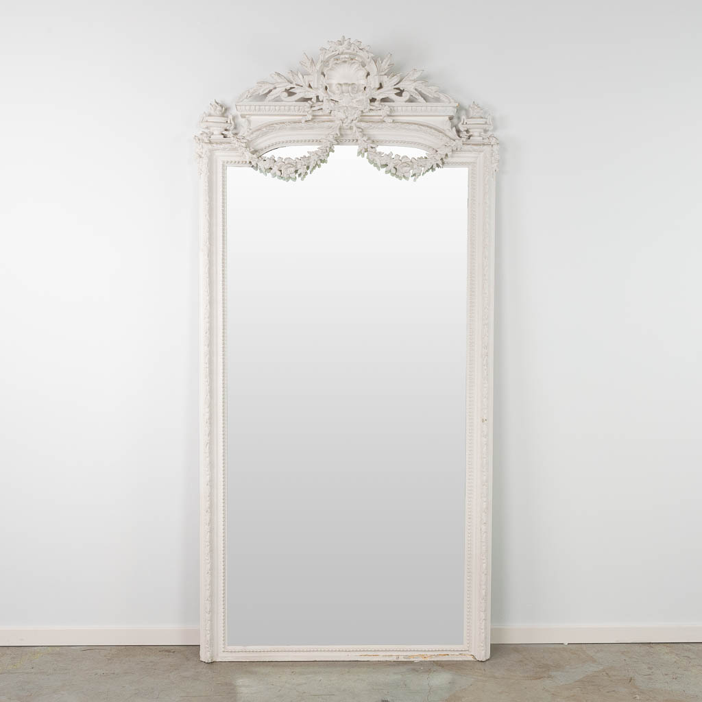 A white patinated mirror in Louis XVI style. 