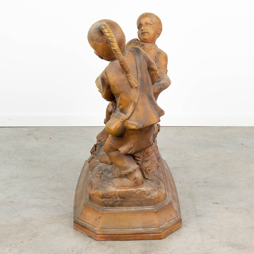 A large terracotta statue of two children and a basket, made of terracotta and marked 